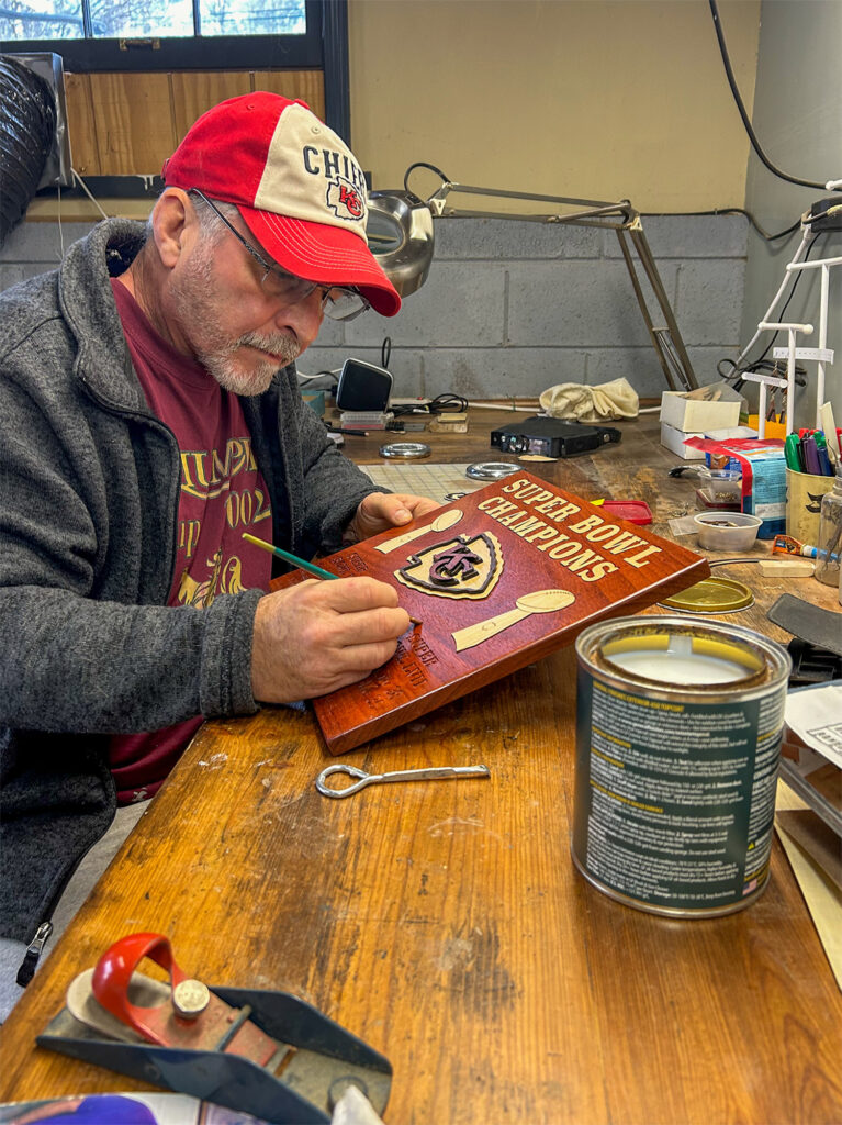 A man working on a sign in his workshop.