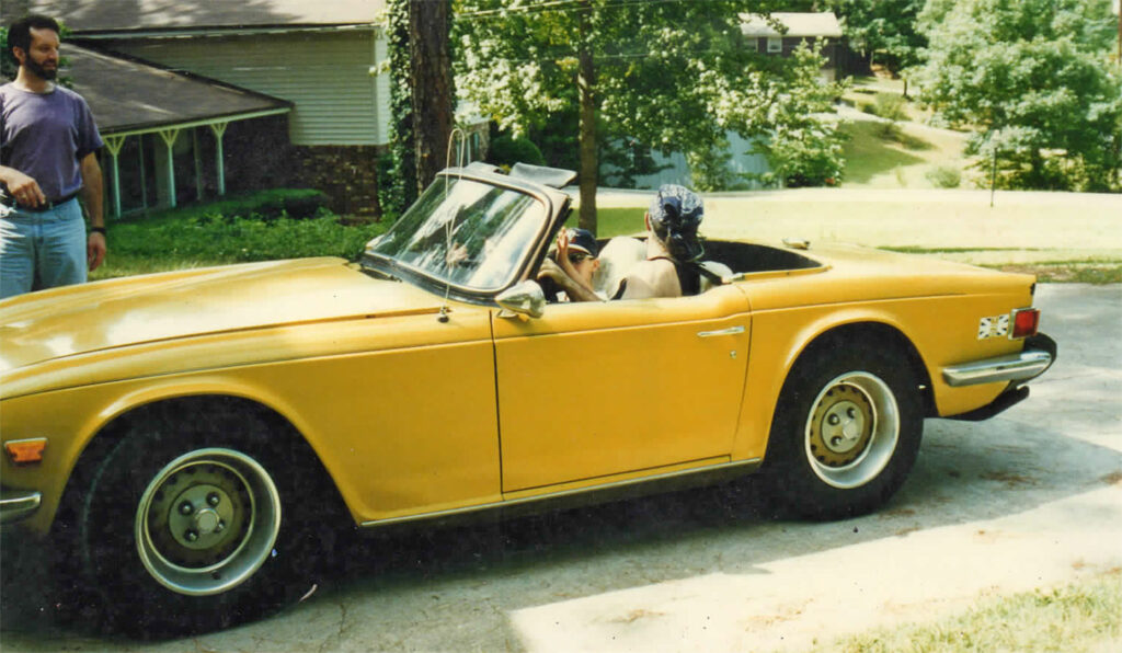 A yellow car with two dogs in it