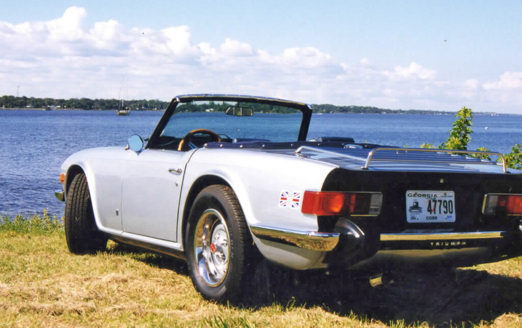 A white car parked on top of grass near water.