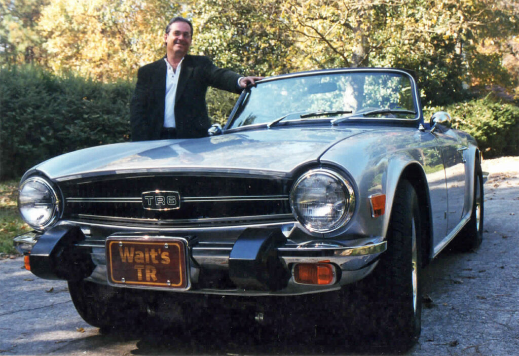 A man standing next to an old car.