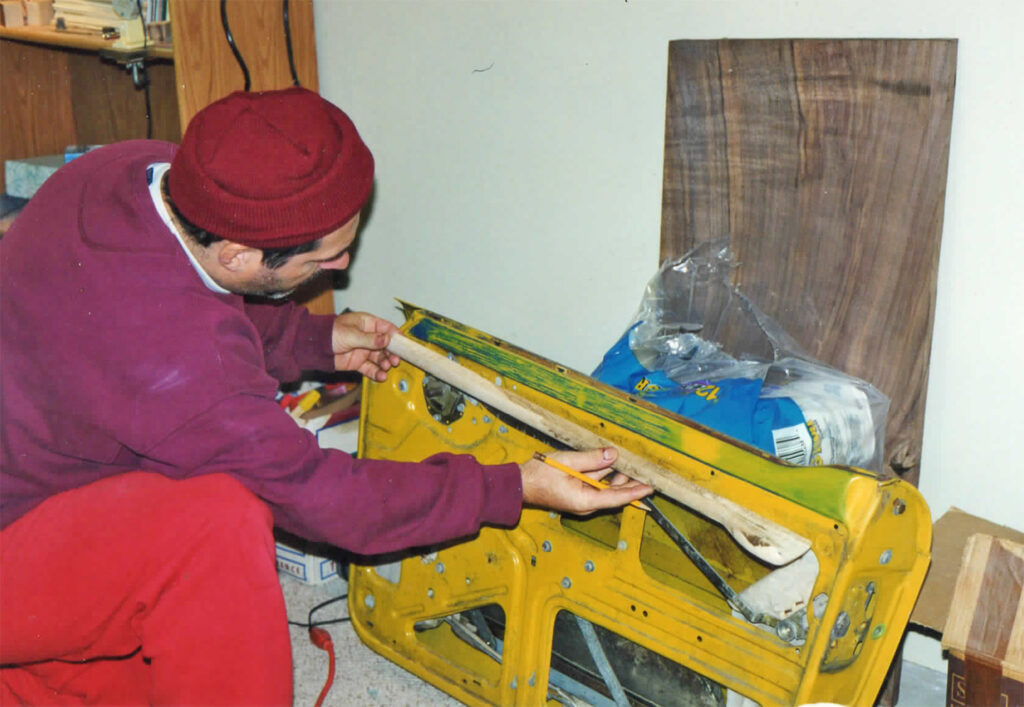 A man in red shirt and hat working on a yellow machine.