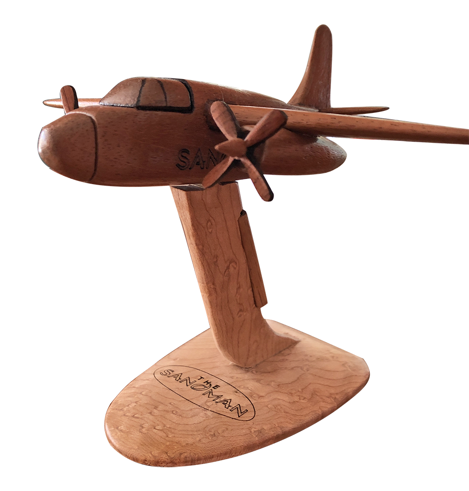A wooden airplane model on display in front of a black background.