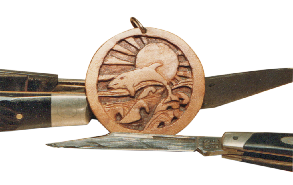 A wooden medallion with a dolphin on it.