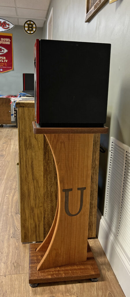 A wooden stand with a speaker on top of it.