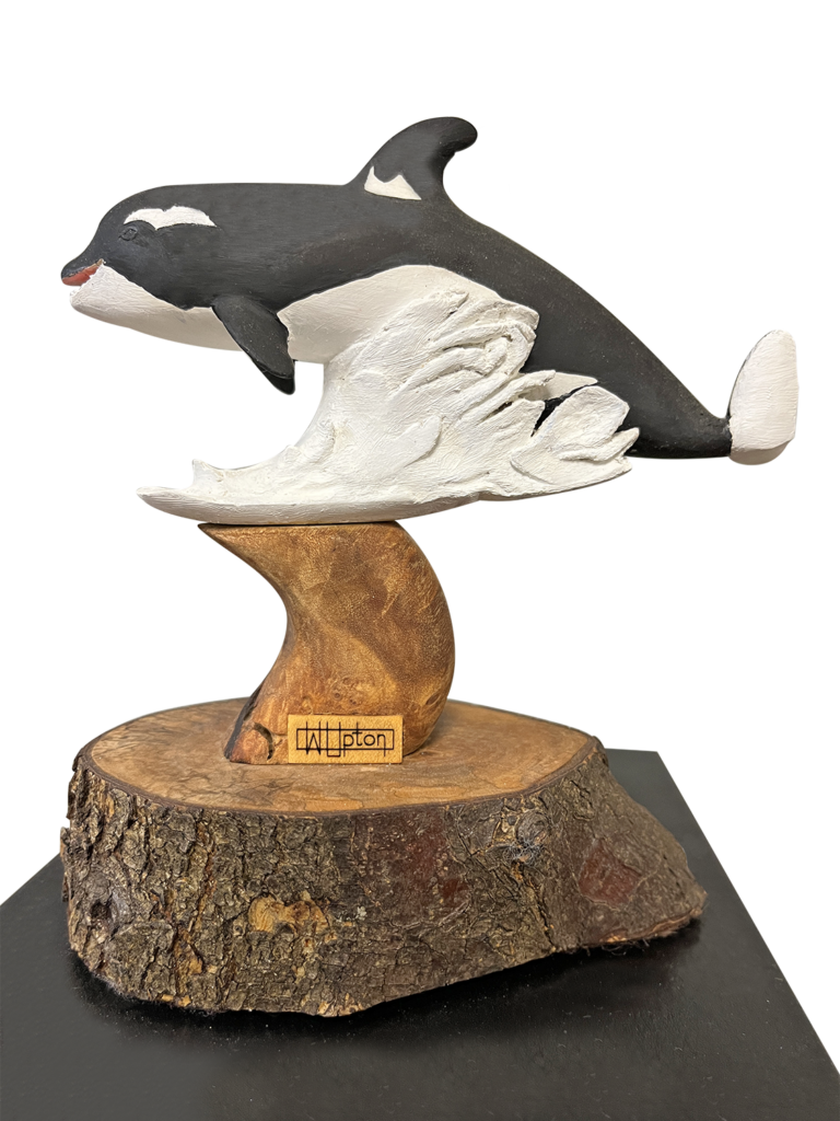 A sculpture of a whale on top of a tree stump.
