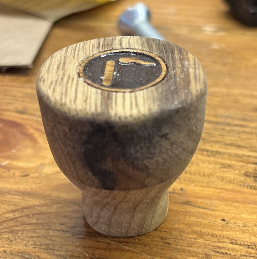 A wooden knob with the letter f on it.