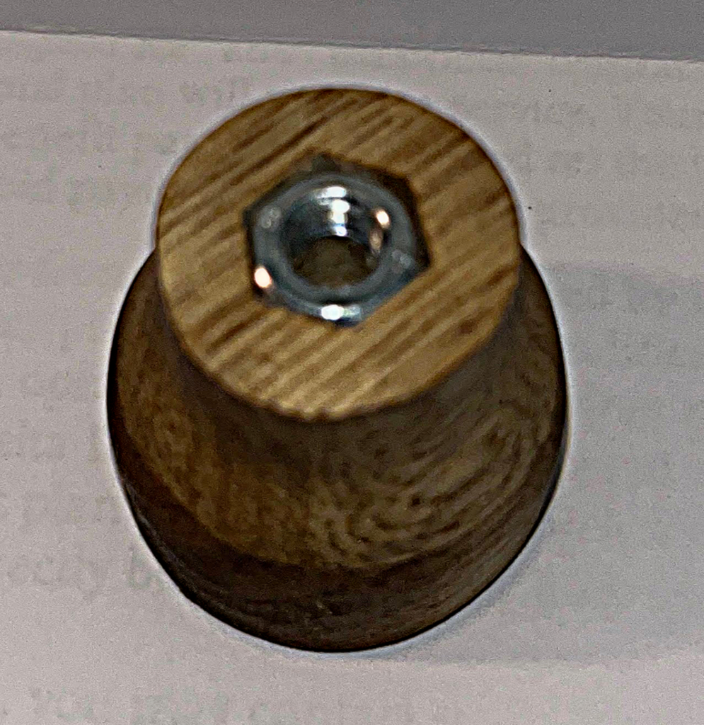 A wooden nut with a metal nut on top.