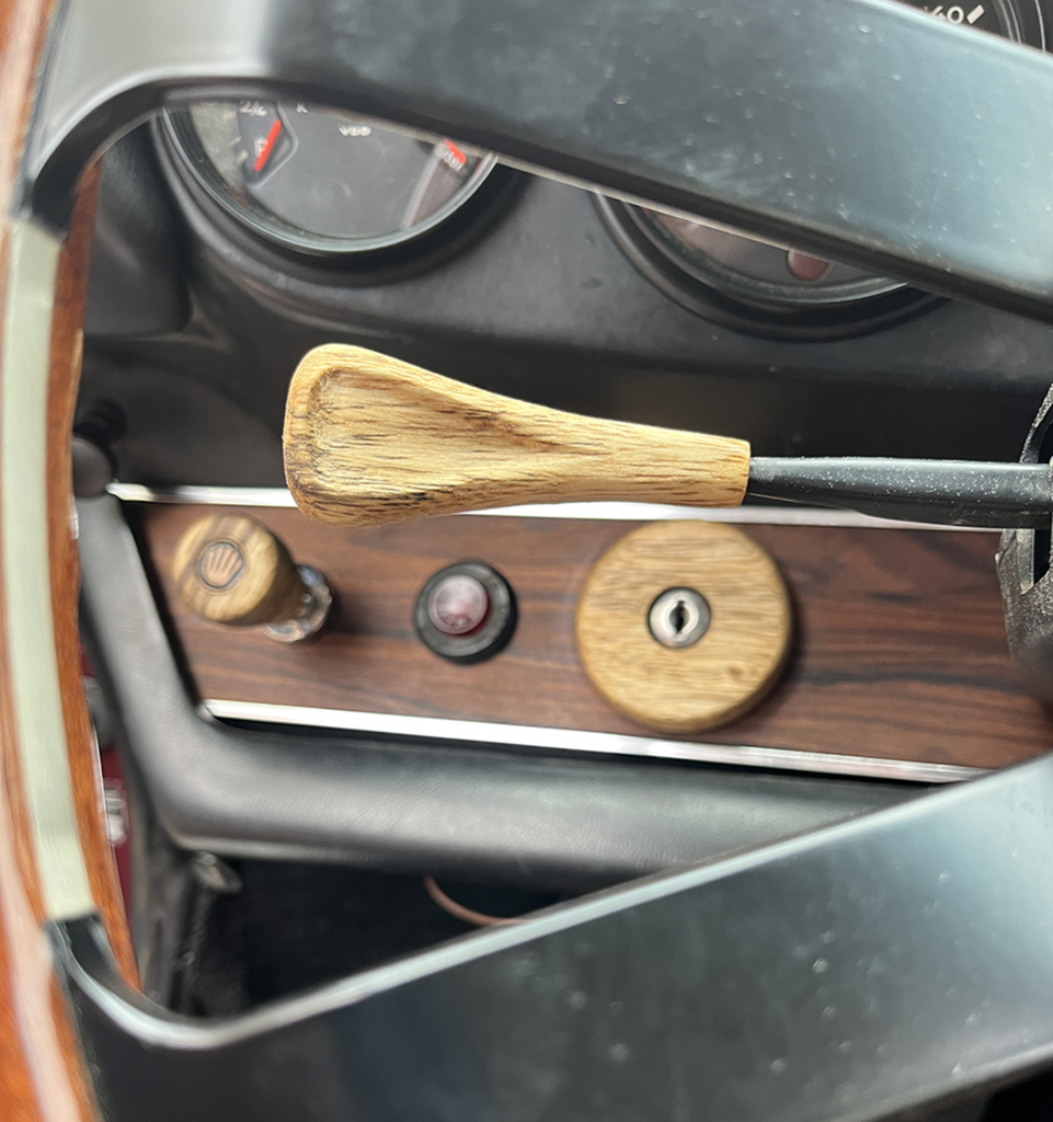A wooden handle in the center of a car dashboard.